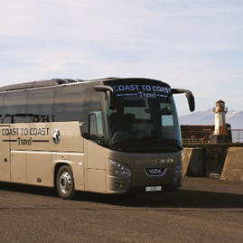 Coast to Coast Travel coach parked at Ardrossan Harbour with a small lighthouse in view behind the coach